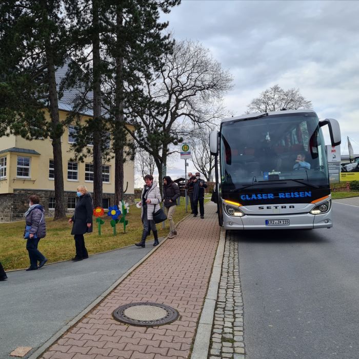 Das Bild zeigt einen Reisebus, der am Straßenrand hält und bei dem Menschen aussteigen.